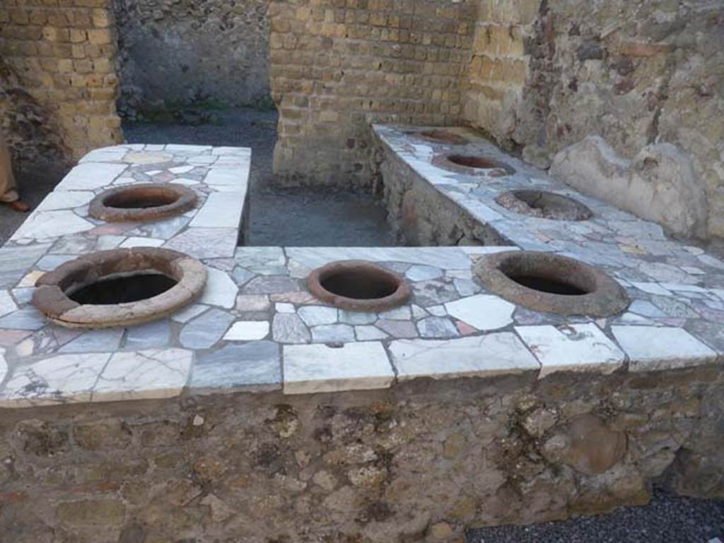 II.6/7 Herculaneum, September 2015. Looking south at northern end of counter/podium. At the rear of the counter is the doorway leading into the two rear rooms.